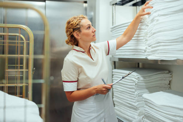 istock Caucasian hotel maid checking clean bed sheets in laundry 1500036500
