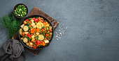 Vegetable stew with fresh herbs on a dark background. Vegetarian food.
