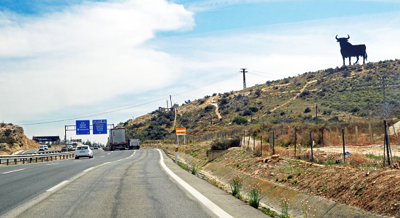 Four-lane A7 coastal highway in South-Eastern Spain, passing the famous Osborne bull billboard, declared national heritage