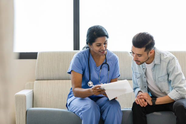 Young man and female doctor review the medical chart together stock photo