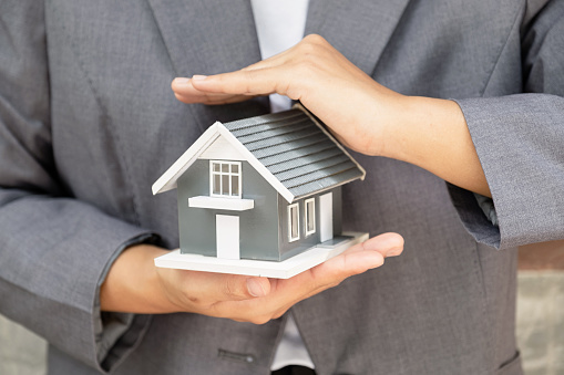 Real estate agent hands holding the home model or Sales presenting home insurance.