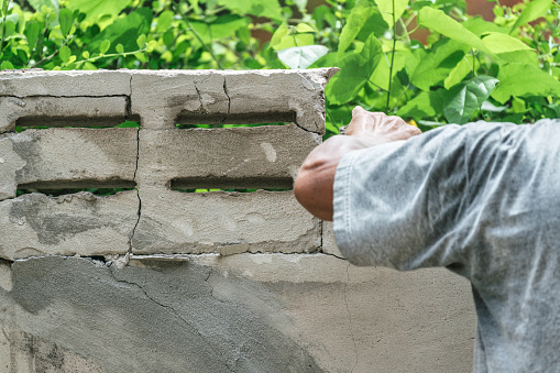 Hand of worker using hammer smashing and demolish on brick block wall at construction site