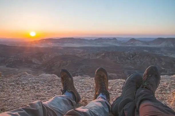 two men with hiking shoes against the sun setting