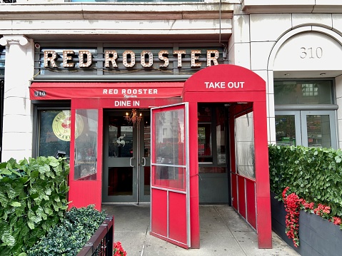 New York, NY USA - June 17, 2023 : Bulb sign and red front entrance to Red Rooster restaurant on Lenox Avenue in Harlem, New York City