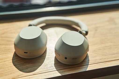 Large white wireless headphones lying on a wooden table. High quality photo