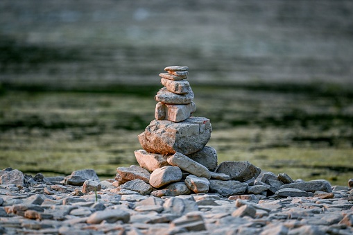 A tranquil landscape featuring a series of stone stacks precariously perched on top of small rocks by the edge of a body of water