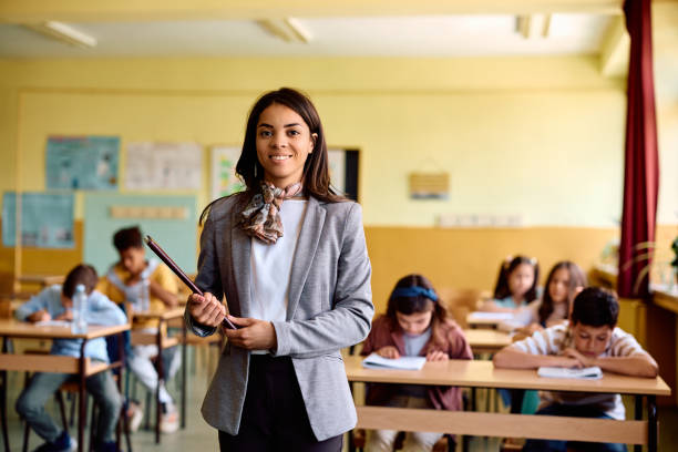 istock Happy elementary school teacher in the classroom looking at camera. 1500076332