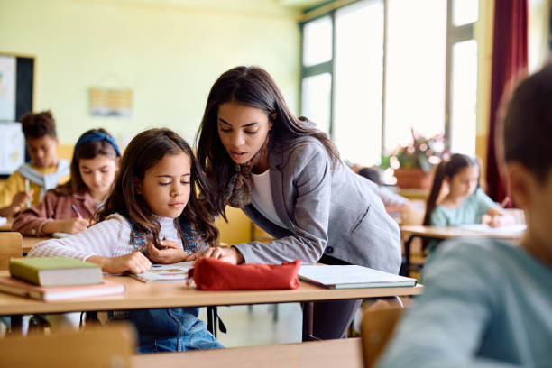 istock Hispanic elementary school teacher helping her student in learning in the classroom. 1500076363
