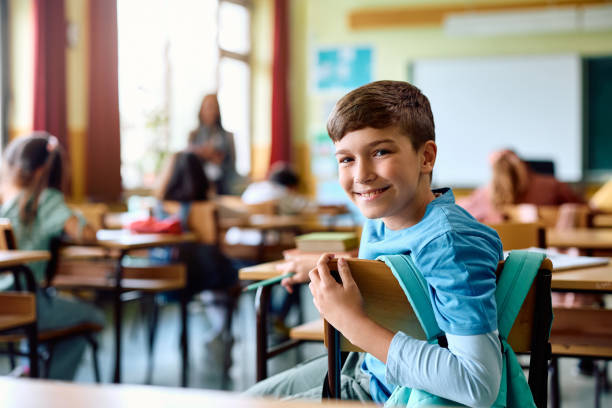 istock Happy schoolboy attending a class in the classroom and looking at camera. 1500076463