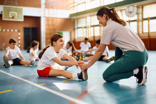 istock Sports teacher assisting her students in exercising during PE class at school. 1500076533