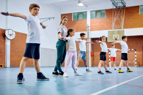 istock Sports teacher assisting her students during physical activity class at elementary school gym. 1500076577