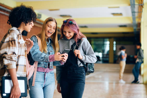 istock Cheerful high school friends using smart phone during a break in hallway. 1500076610
