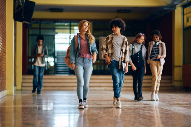istock Happy high school friends talking while walking through hallway at school. 1500076706