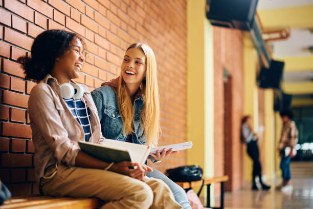 istock Happy female high school students laughing while learning in a hallway. 1500076768