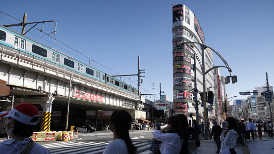 May 24, 2023 - Taito City, Japan: Pedestrians wait at the crosswalk outside Ueno Station and Ameya Yokocho, the former candy store alley. Spring afternoon with a clear sky.