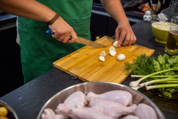 a blond man with a beard and a green apron prepares dinner in his home kitchen. - routine foods and drinks clothing household equipment imagens e fotografias de stock