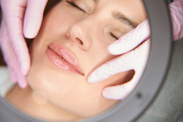 Beautician examines the nasolabial folds of patient after beauty injections stock photo