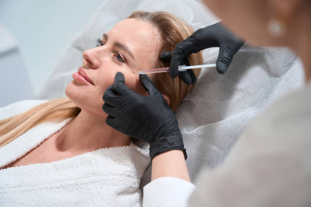 Female blonde gets a rejuvenating injection in her cheeks stock photo