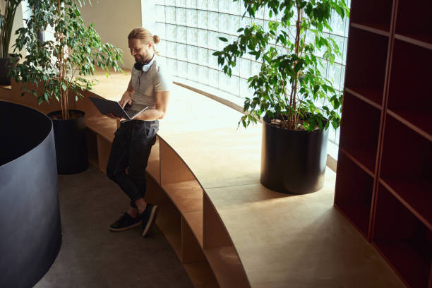 istock Smiling guy with laptop is located at large textured window 1500084922