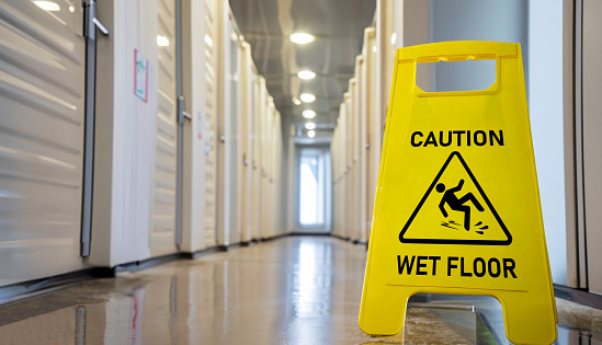 Yellow wet floor caution sign in wet corridor