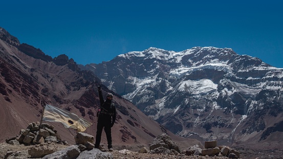 Young climber man with raised fist with Aconcagua mountain in the background on a sunny day