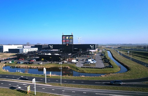 Zwaag, Netherlands – February 14, 2023: Parking lot with fast food restaurants mcdonald's, kentucky fried chicken KFC, AVIA gas station and subway with advertisement along the highway