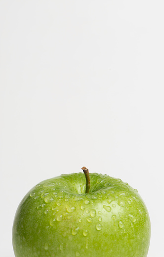 Close-up of wet green apple against white background.