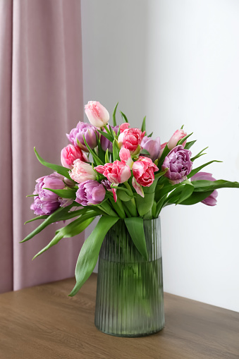 Beautiful bouquet of colorful tulip flowers on wooden table indoors