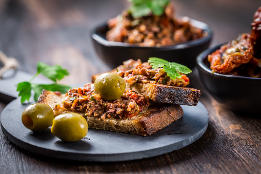 Crispy crostini with tapenade and ingredients. Tapenade - delicious olive paste, French cuisine