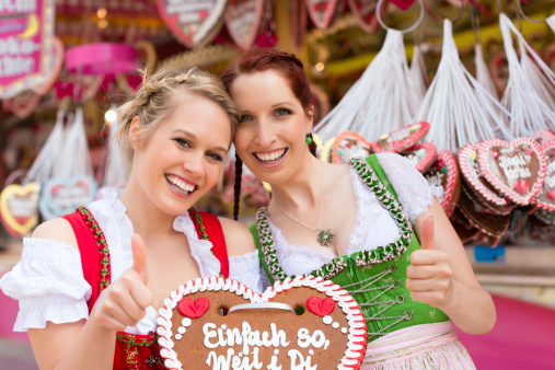 Young women in traditional Bavarian clothes - dirndl or tracht -with a gingerbread souvenir heart on a festival or Beer Fest