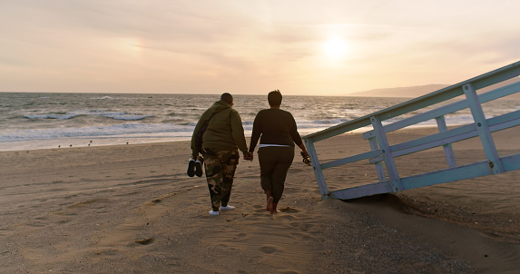 Two African American women walking on the Santa Monica beach at sunset.