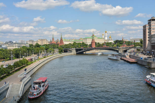 Moscow, Russia, September 28, 2023: Illuminated Red brick tower and Kremlin at night, tour boat cruising on the Moskva River
