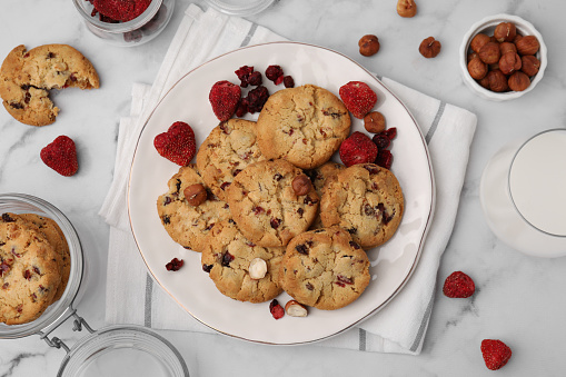 Cookies with freeze dried fruits and nuts on white marble table, flat lay