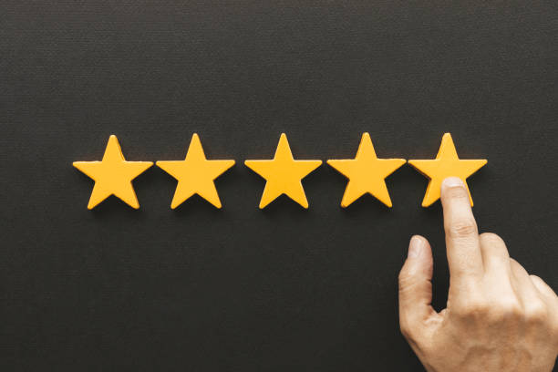 Five star rating feedback Five star rating feedback. Hand is pointing at last yellow star shape in front of black background. Giving best score point to review the service first class stock pictures, royalty-free photos & images