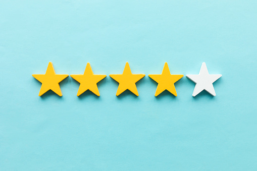 Five star rating feedback. Giving score point to review the service. Four yellow stars and one white.