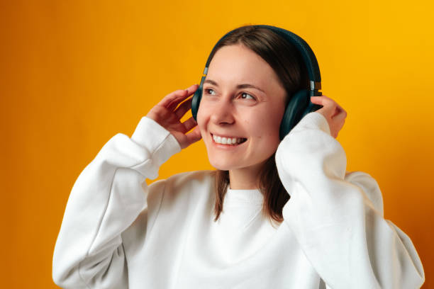 Close up shot of a dreaming smiling woman listening to the music in headphones. stock photo