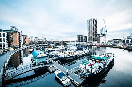 Boats and yachts moored at Limehouse Basin Marina in London with Canary Wharf in the background