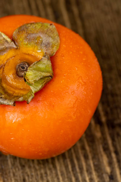テーブルの上の熟したオレンジ色の柿全体 - autumn market freshness vertical ストックフォトと画像