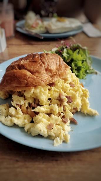 istock Croissant with scrambled eggs with bacon cubes and lettuce 1500109798