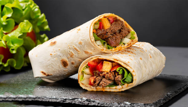 burritos owija się wołowiną i warzywami na czarnym tle. burrito wołowe, meksykańskie jedzenie. - barbecue beef close up multi colored zdjęcia i obrazy z banku zdjęć