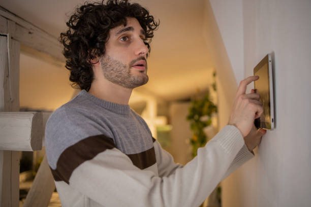 istock Young man adjusts the temperature at home with a device on the wall 1500126076