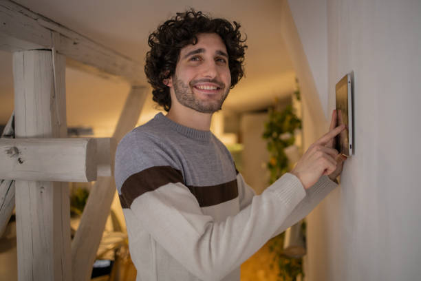 istock Young man adjusts the temperature at home with a device on the wall 1500126082