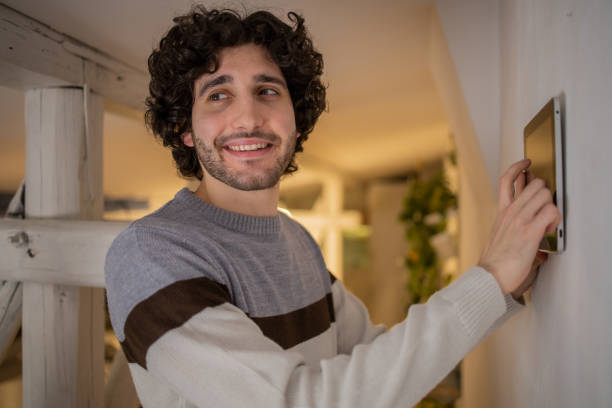 istock Young man adjusts the temperature at home with a device on the wall 1500126083