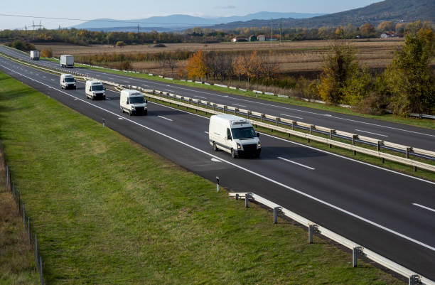 istock Four White delivery van on the highway. White modern delivery small shipment cargo courier van moving fast on motorway road to city urban suburb. The business distribution and logistics express service. 1500127579