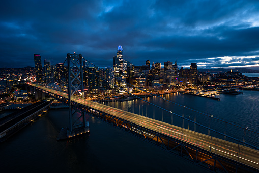 Aerial view of San Francisco at night, looking beyond the Bay Bridge towards Financial District skyscrapers and the Embarcadero.