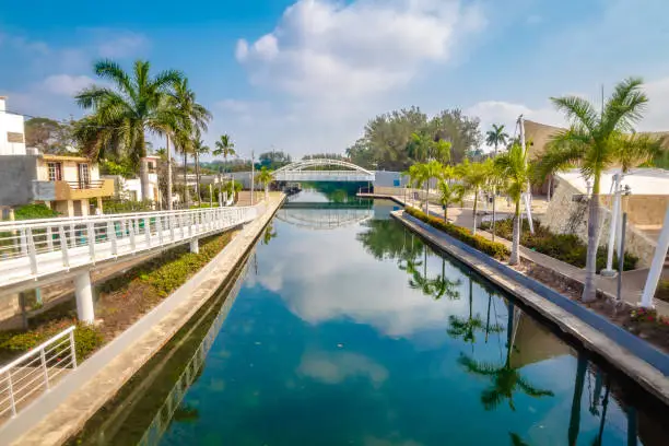 Calles de una ciudad tropical junto a un rio verde esmeralda, cielo azul con nubes, calles de Tampico tamaulipas, rio de la laguna del carpintero