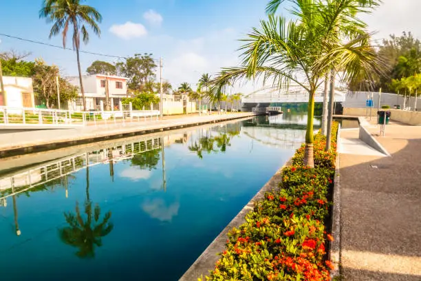 Calles de una ciudad tropical junto a un rio verde esmeralda, cielo azul con nubes, calles de Tampico tamaulipas, rio de la laguna del carpintero