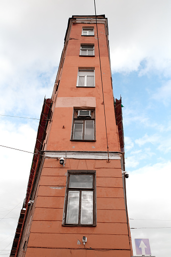 Old unusual acute-angled residential building in the historical center of St. Petersburg, Russia. Cloudy gray day, low angle view