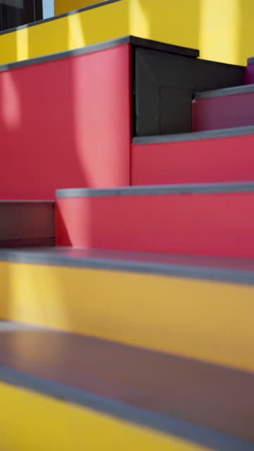 Unrecognized woman wearing jeans and sandals walking up quickly on the colorful stairs, red and yellow
