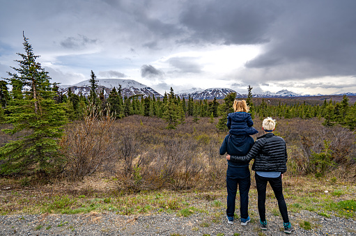 Mother, father, and daughter enjoying a view of Denali Mountain in the beautiful dramatic alpine scenery of Denali National Park Alaska, USA
